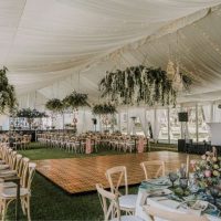 Elegant tent interior decorated with drapery and floral arrangements for an event.