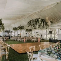 Elegant tent interior decorated with drapery and floral arrangements for an event.