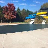Large commercial pool covered with a tightly secured green mesh safety cover.